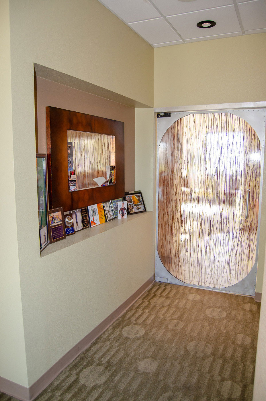 The image depicts an interior space with a wall-mounted mirror reflecting a hallway, and a large circular decorative element on the right side.