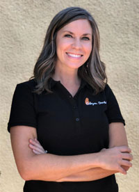 The image is of a woman standing outdoors, wearing a dark polo shirt with the logo  Debra s Dream  visible on it. She has short hair and is smiling at the camera.