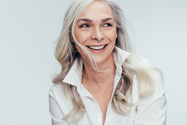 Woman with short hair, wearing a white shirt and smiling.