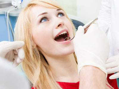 A woman in a dental chair receiving dental treatment, with a dental professional performing the procedure.