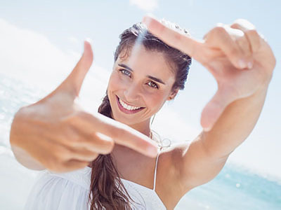 A woman is smiling and pointing towards the camera with her index finger.